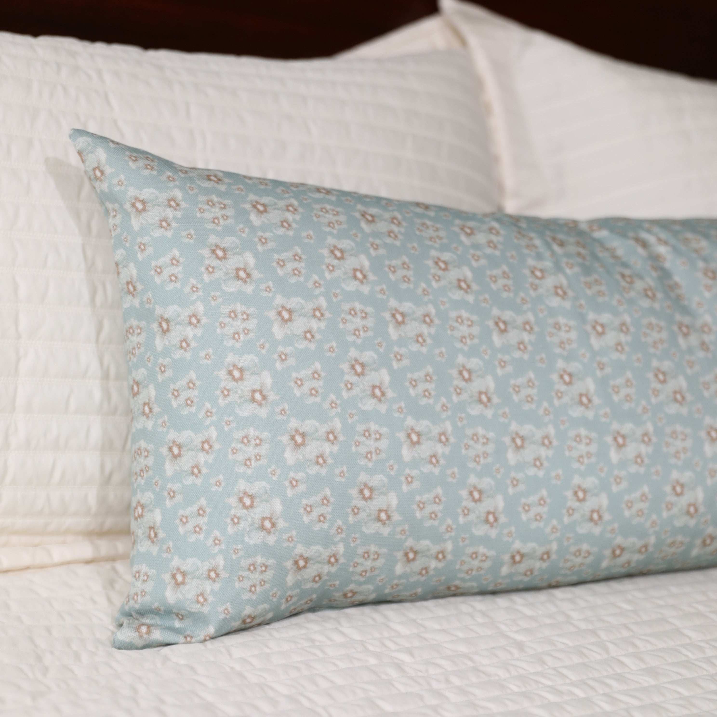 Luxury floral bolster pillow featuring a delicate cottage garden pattern with soft botanical detail, handcrafted in England for timeless and layered interiors.