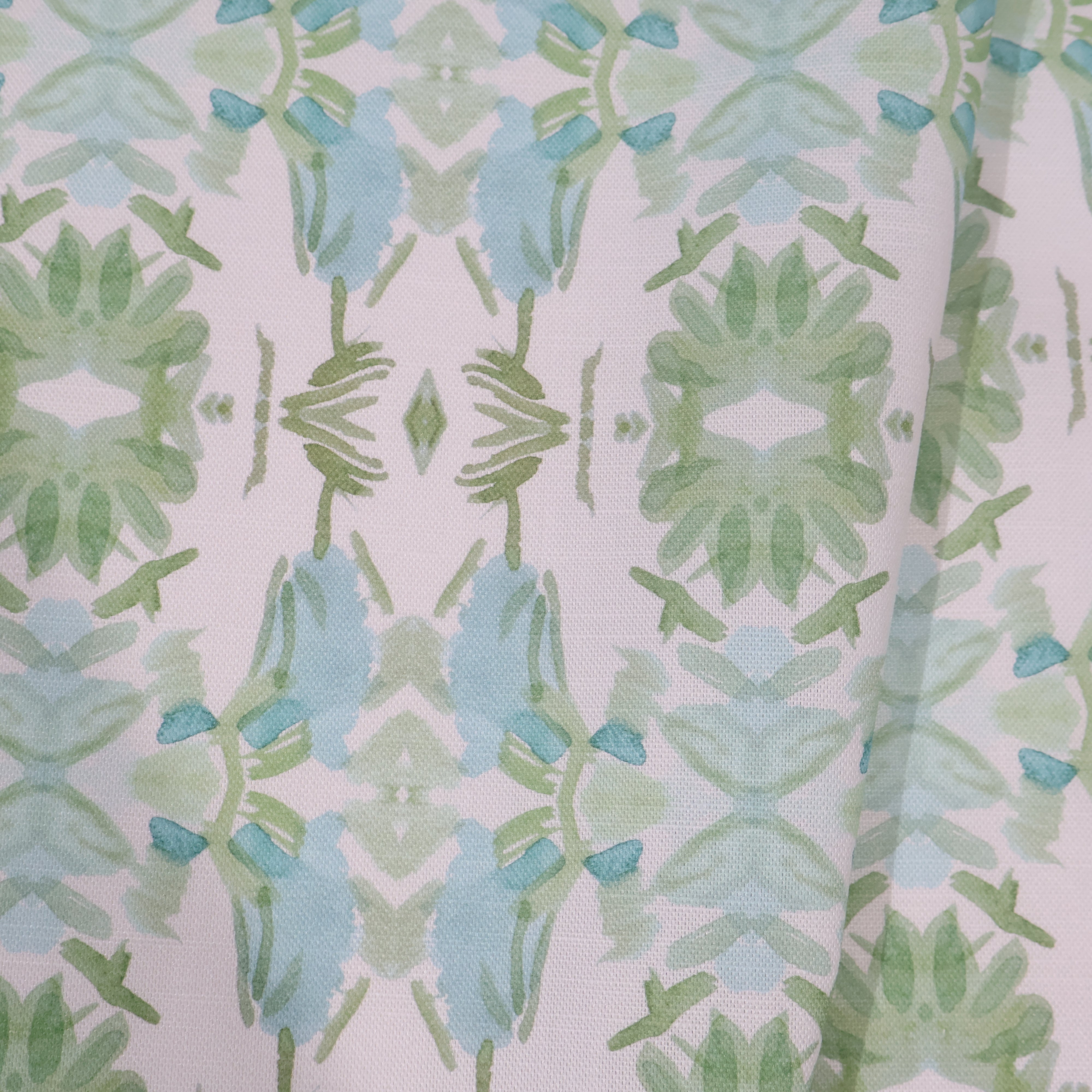 Luxury botanical fabric featuring layered wildflower patterns in sage green, soft blue, and natural tones for modern traditional and collected interiors.