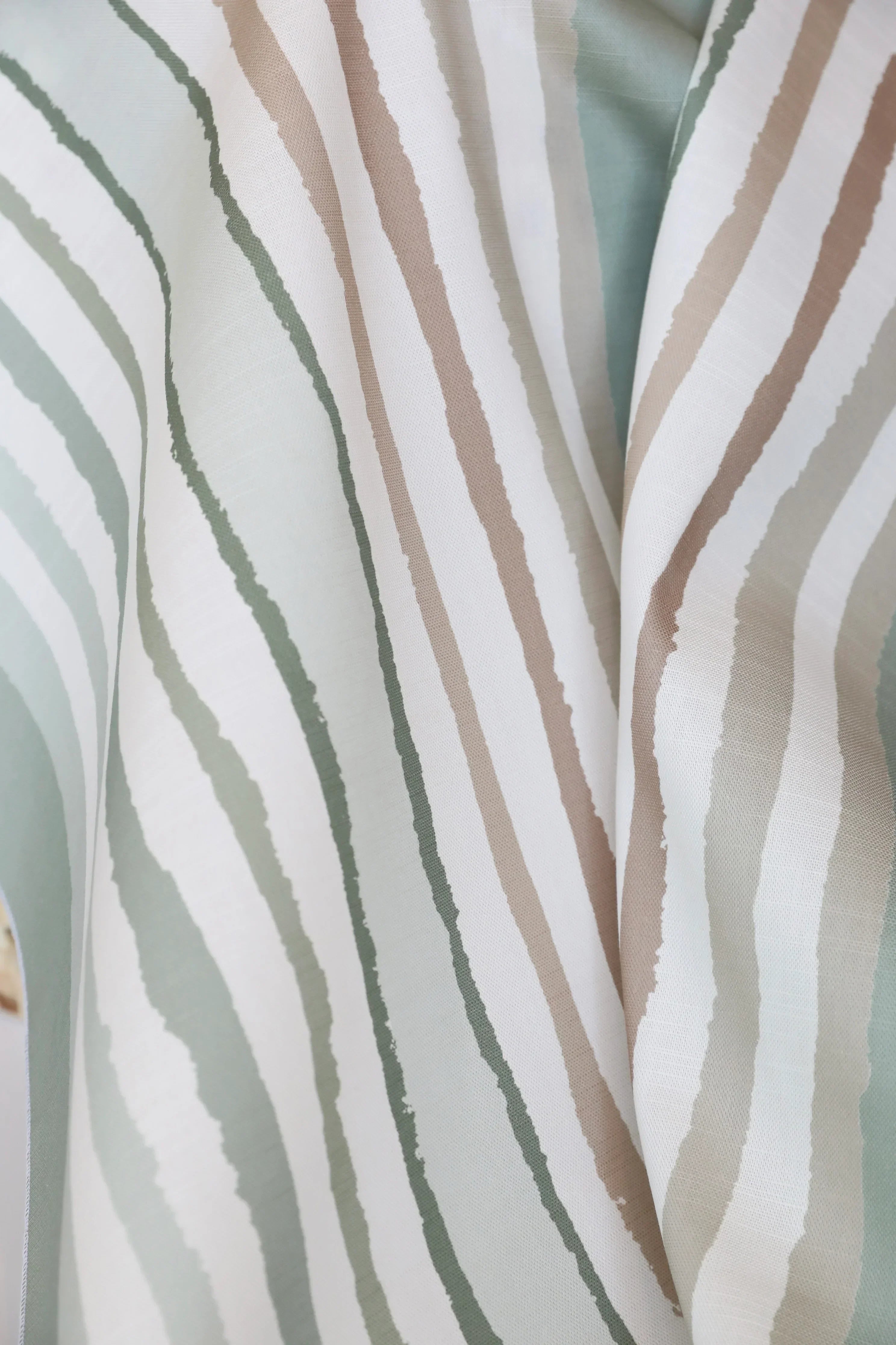 Close-up of striped  luxury fabric with horizontal lines in beige, green, and white.