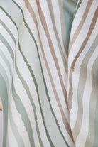 Close-up of striped  luxury fabric with horizontal lines in beige, green, and white.