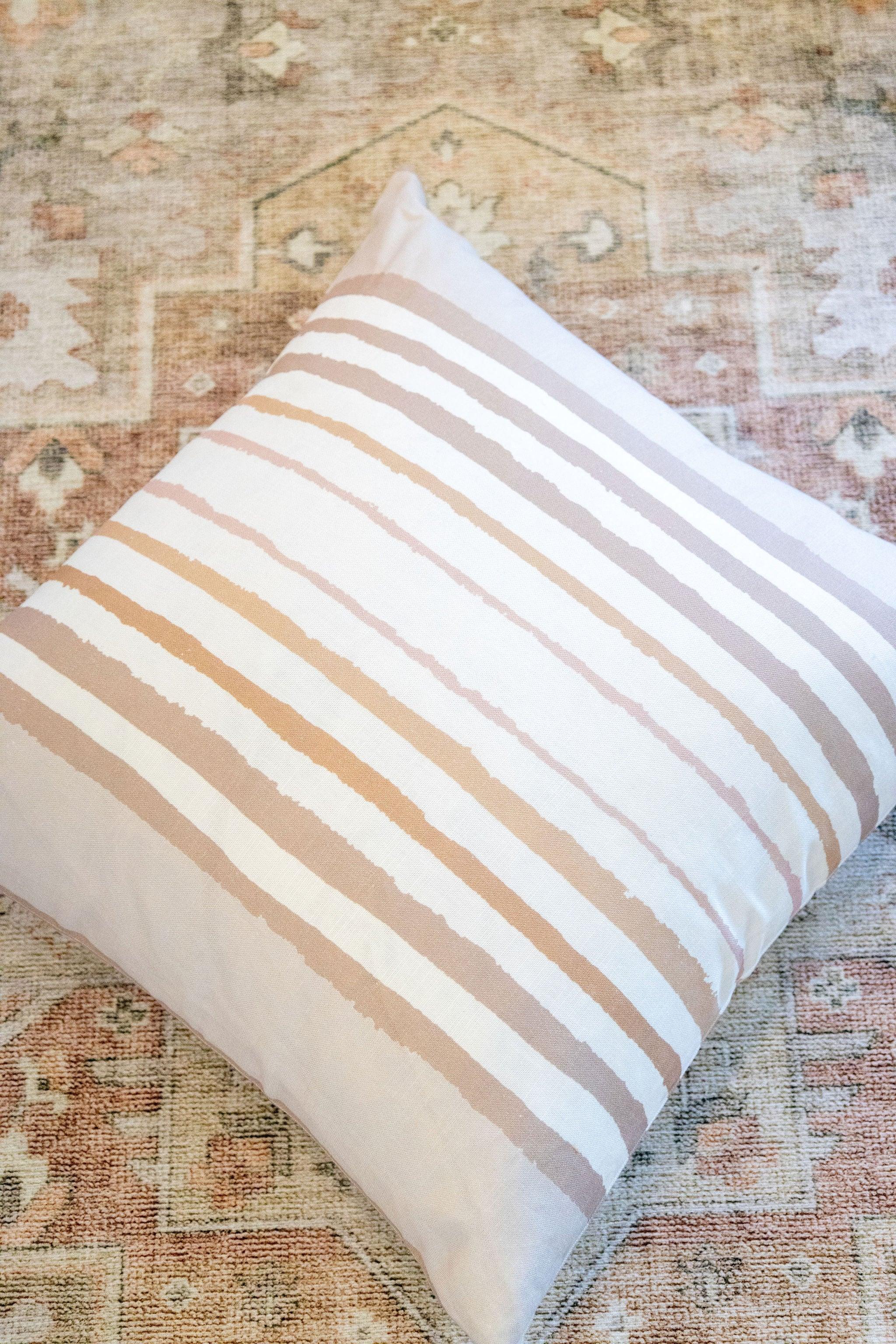 Brother Stripe in Neutrals Luxury Pillow by Truett Designs featuring an artistic stripe pattern in warm neutral tones. Handcrafted in England from sustainably printed luxury fabric, this designer decorative pillow adds structure, texture, and timeless elegance to sofas, beds, and accent chairs. A versatile favorite for interior designers, it pairs beautifully with florals, botanicals, grasscloth, natural linens, and tailored upholstery in luxury residential interiors.