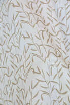 Luxury botanical fabric in warm brass tones with layered painterly organic design, ideal for upholstery, drapery, and sophisticated contemporary interiors.