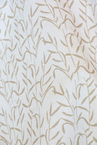 Luxury botanical fabric in warm brass tones with layered painterly organic design, ideal for upholstery, drapery, and sophisticated contemporary interiors.