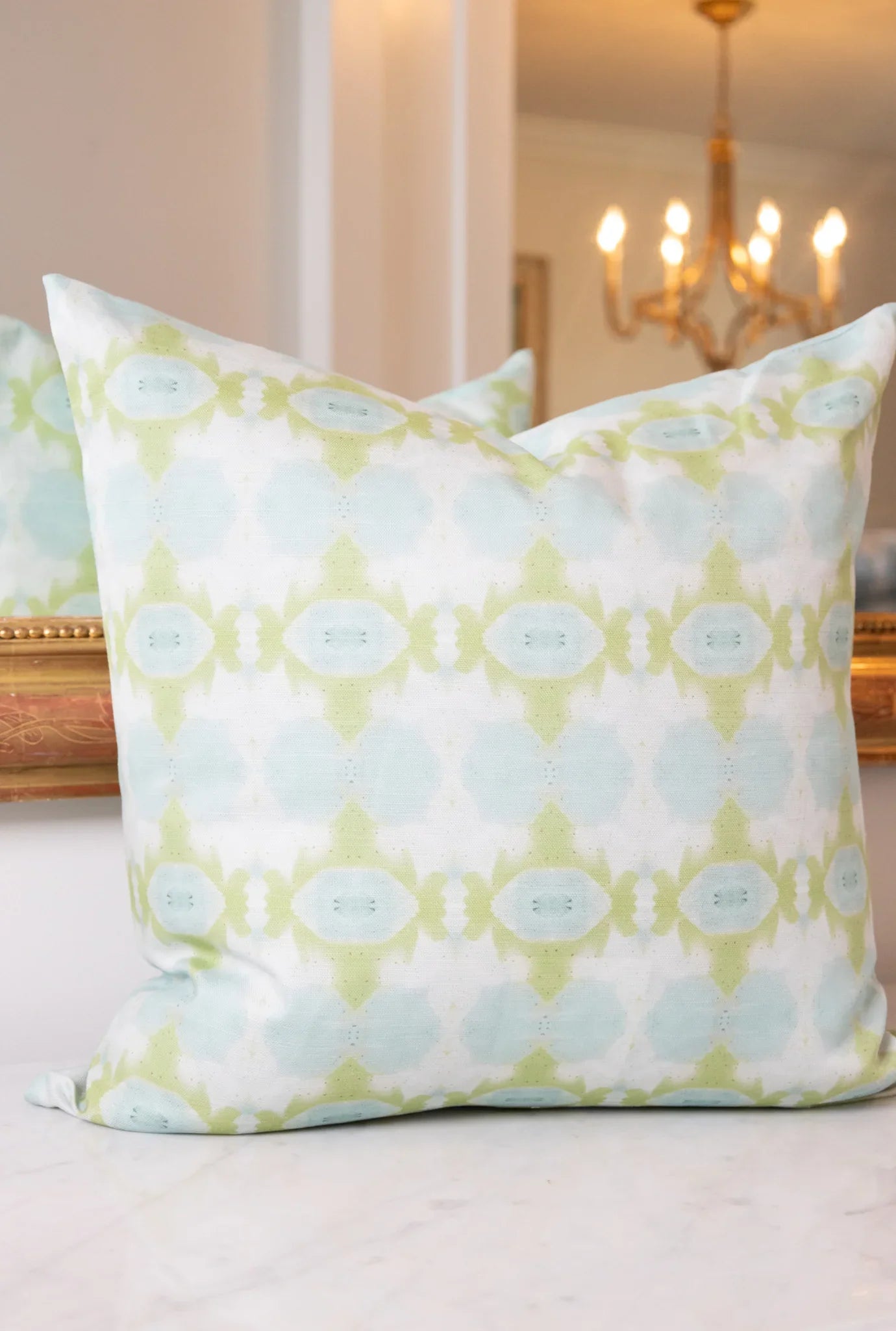 Luxury decorative pillow featuring an abstract small repeat pattern in chartreuse green and soft blue tones, styled for a layered modern traditional interior.
