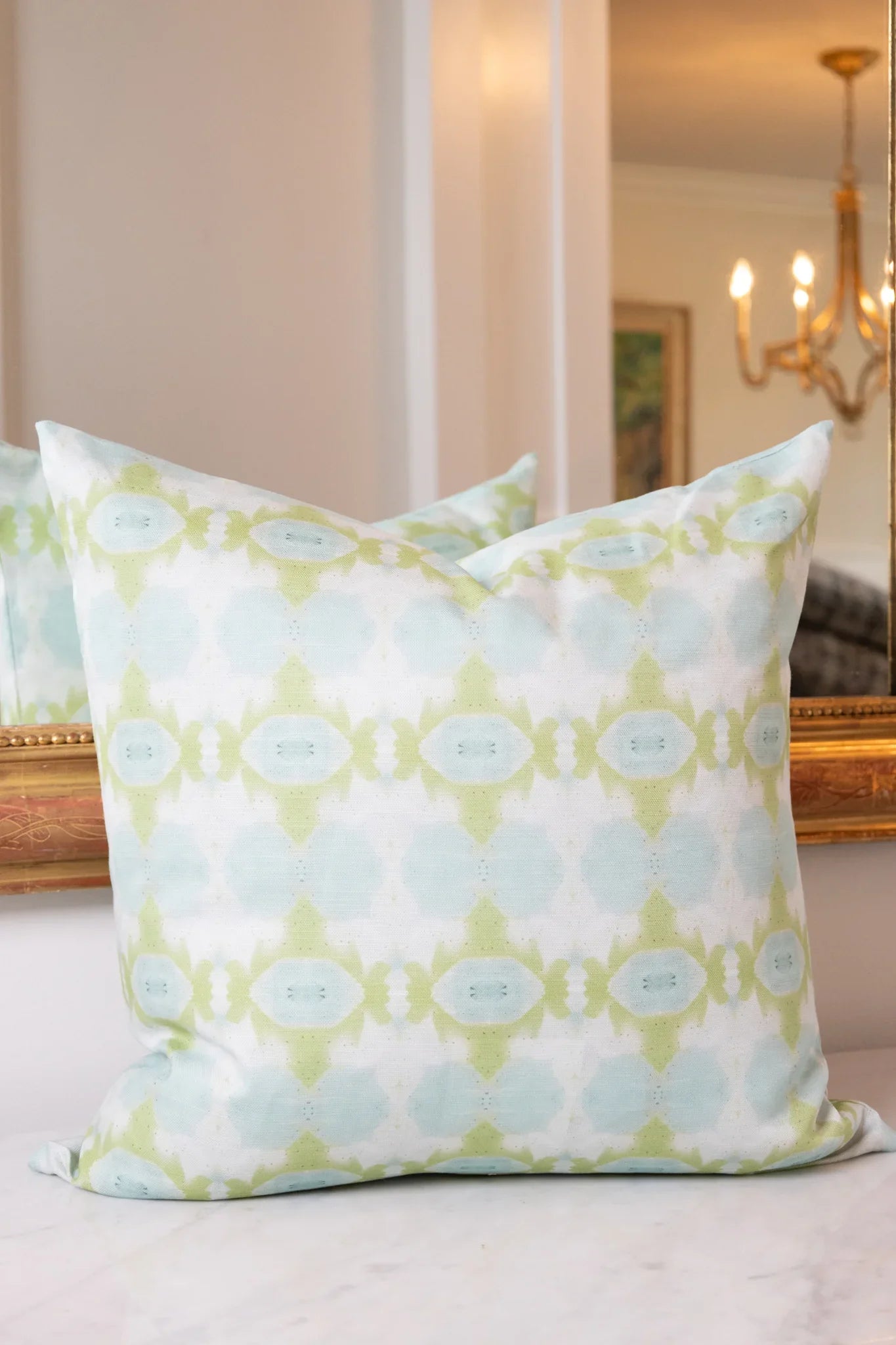 Luxury decorative pillow featuring an abstract small repeat pattern in chartreuse green and soft blue tones, styled for a layered modern traditional interior.