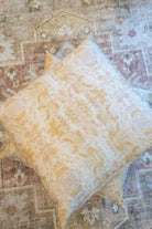 Luxury decorative pillow featuring an abstract topiary-inspired pattern in warm autumn gold and neutral tones, styled for a layered modern traditional interior.