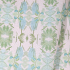 Luxury botanical fabric featuring layered wildflower patterns in sage green, soft blue, and natural tones for modern traditional and collected interiors.